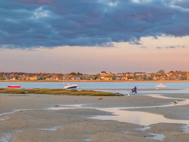Plage avec des bateaux et des gens au coucher du soleil