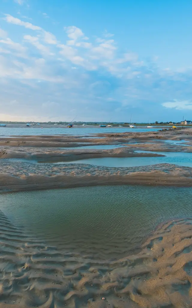 Marée basse sur une plage avec des flaques d'eau et des traces de pas