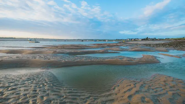 Voiliers amarrés dans un port au coucher du soleil, avec des terrasses animées en arrière-plan