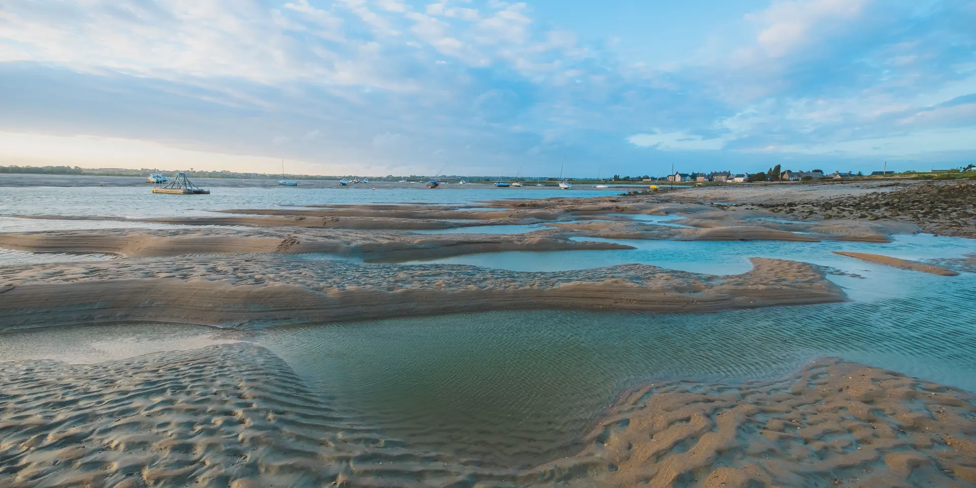 Marée basse sur une plage avec des flaques d'eau et des traces de pas