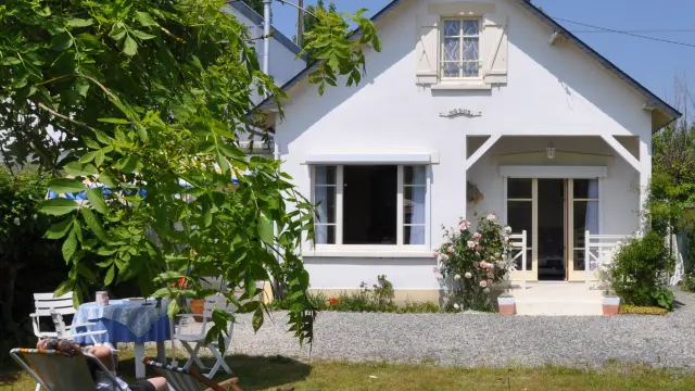 Weißes Haus mit Garten und Liegestühlen