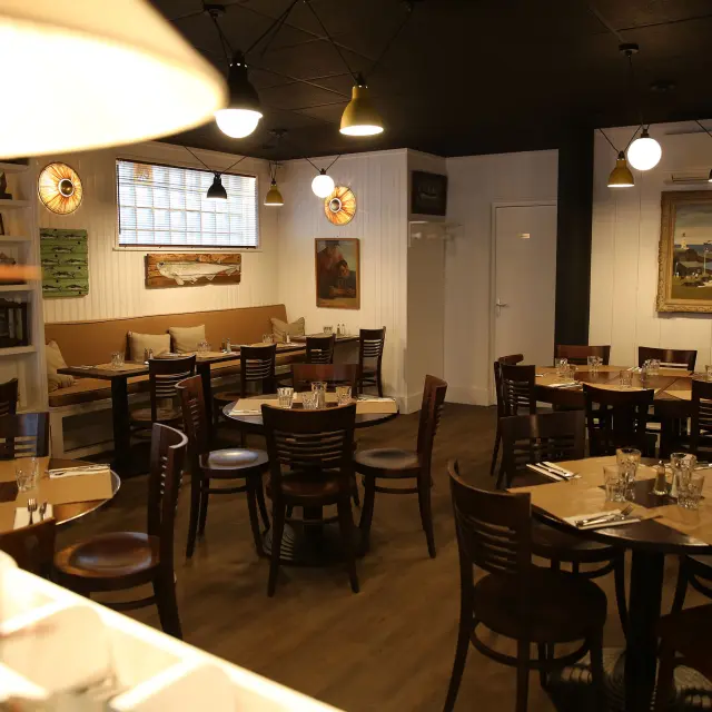Salle de restaurant avec tables en bois et chaises noires, éclairage chaleureux et décoration sobre