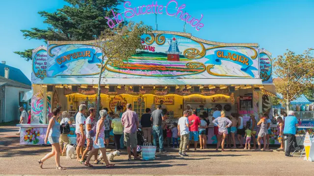A cotton candy stand with people lining up to buy treats