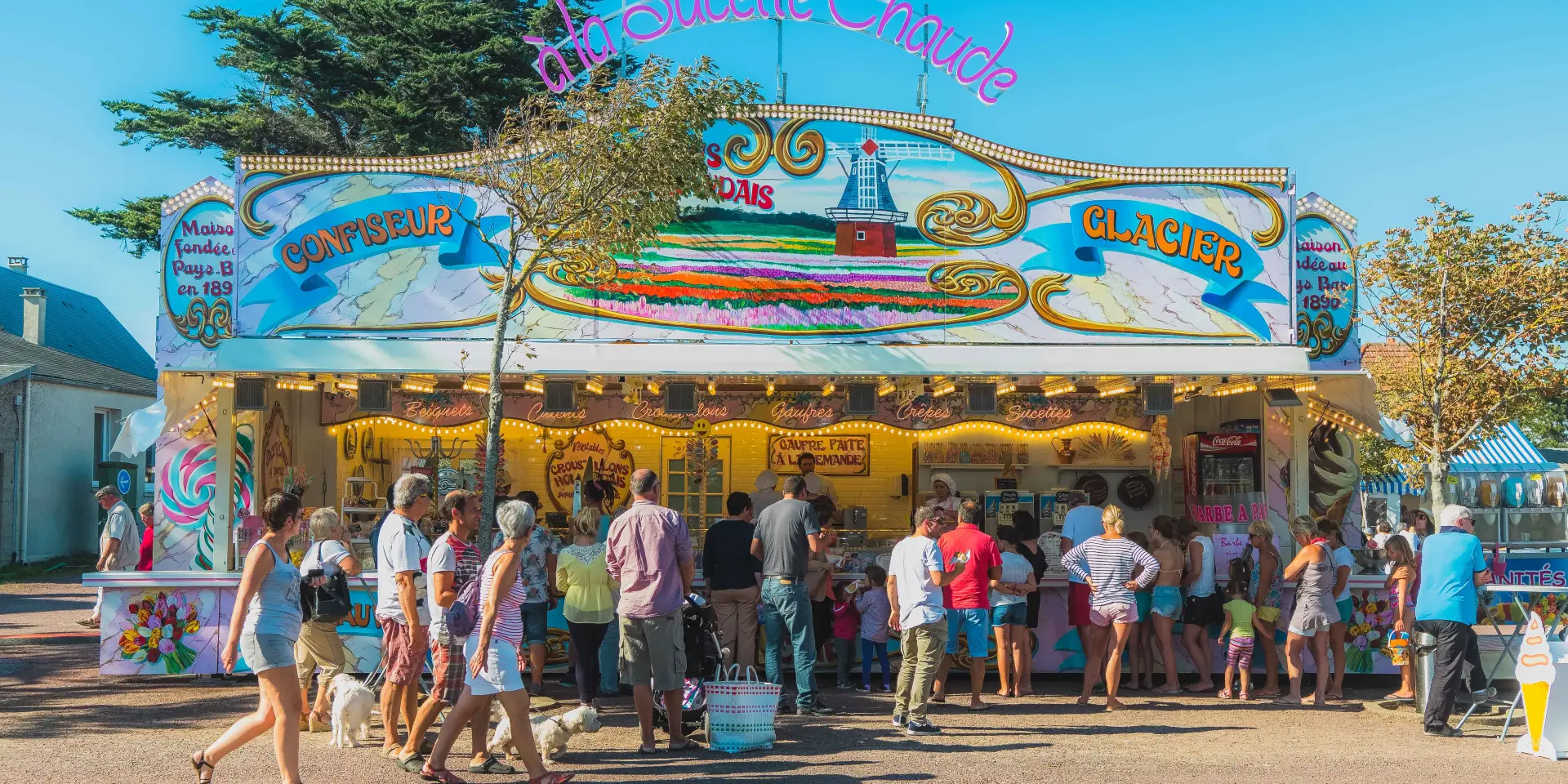 Entrée d’une fête foraine avec manèges et stands colorés, foule de visiteurs
