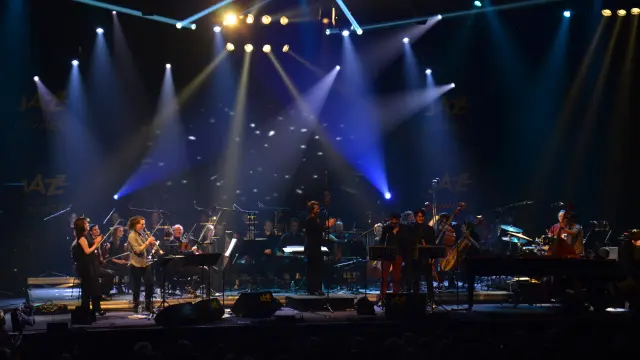 Groupe de musiciens jouant sur une scène éclairée par des projecteurs bleus et blancs