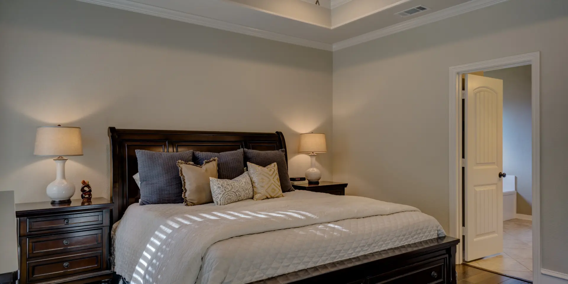 Schlafzimmer mit Kingsize-Bett, zwei Nachttischen und einer offenen Tür