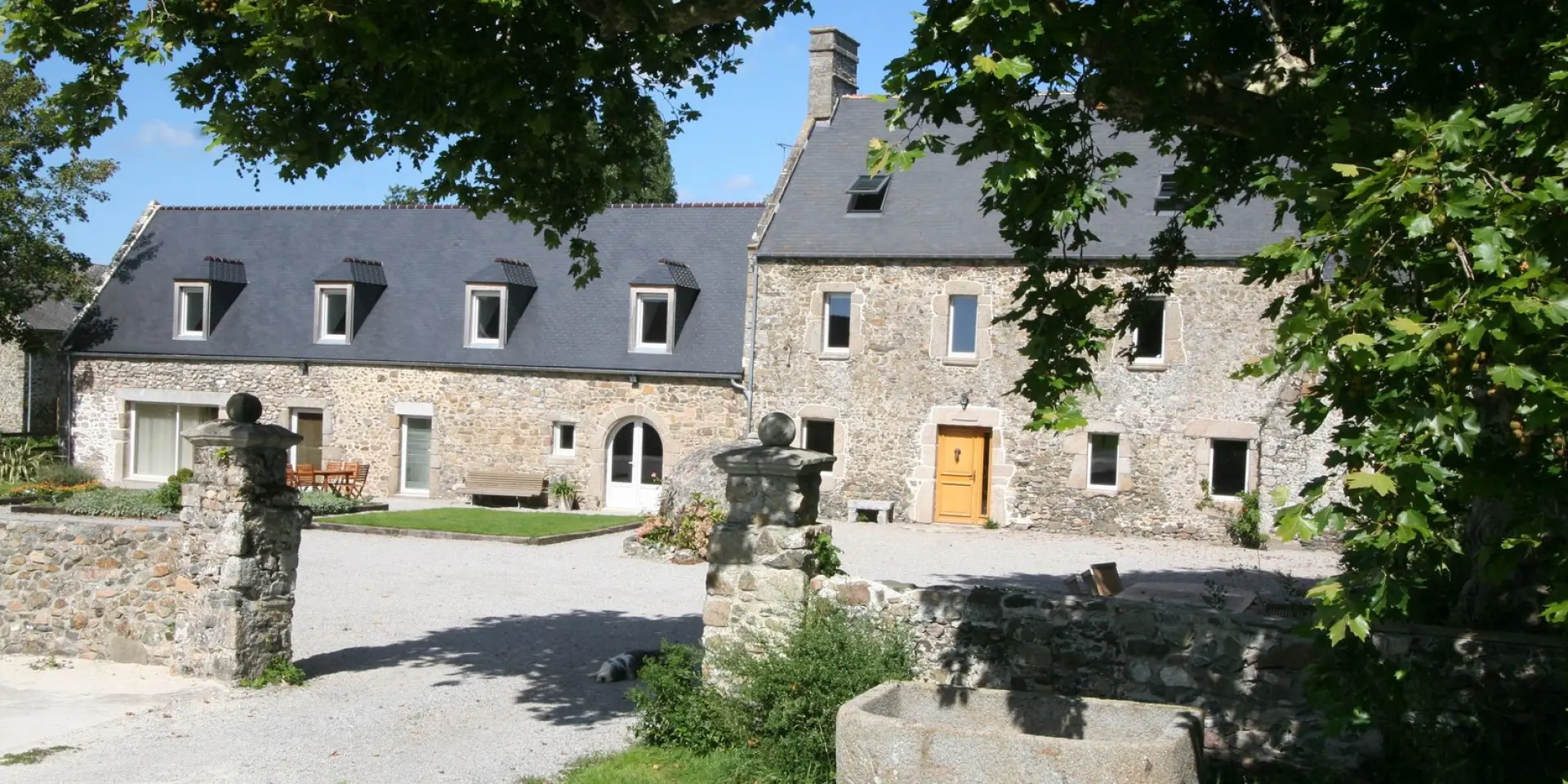 Maison en pierre avec des fenêtres à petits carreaux et des statues dans un jardin