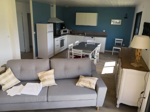 Wohnzimmer mit einem beigen Stoffsofa, einem Holztisch und einem weißen Regal