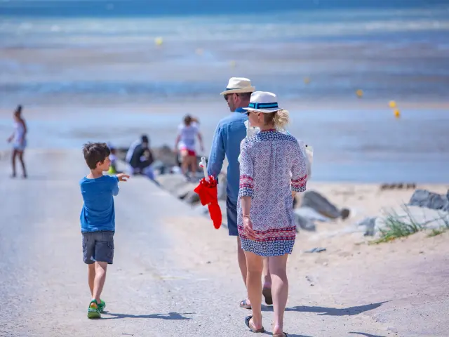 A family walks on a beach path near the water
