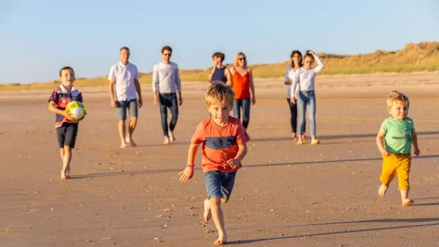 Un groupe d'enfants et d'adultes jouant avec un ballon sur une plage de sable