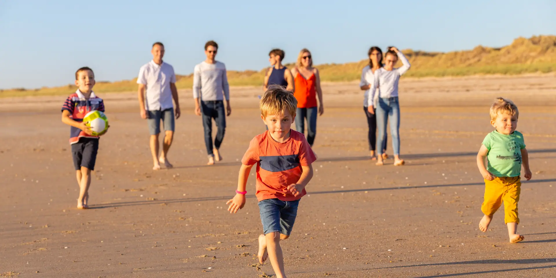Un groupe d'enfants et d'adultes jouant avec un ballon sur une plage de sable