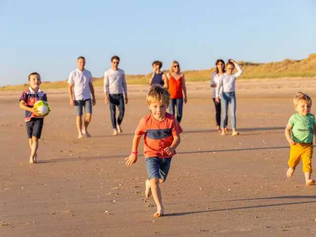 Un groupe d'enfants et d'adultes jouant avec un ballon sur une plage de sable