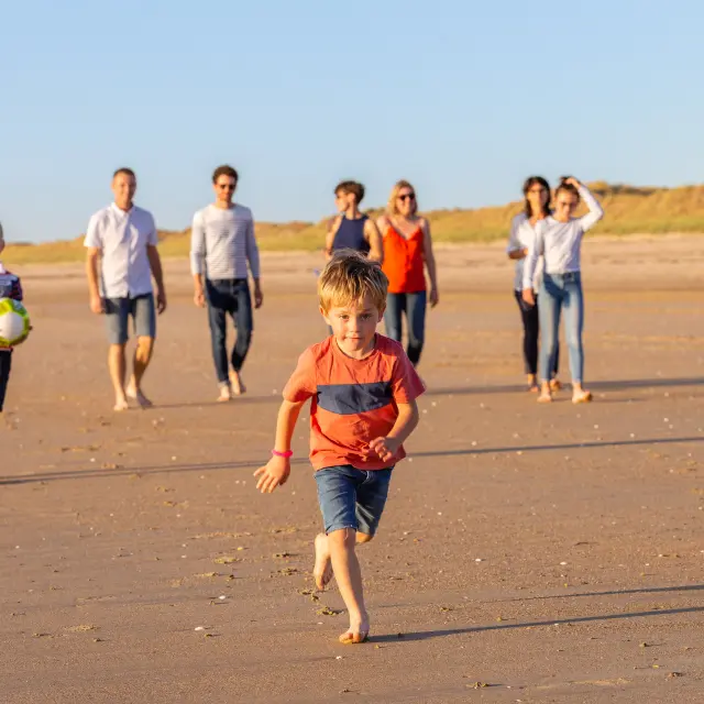 Un groupe d'enfants et d'adultes jouant avec un ballon sur une plage de sable