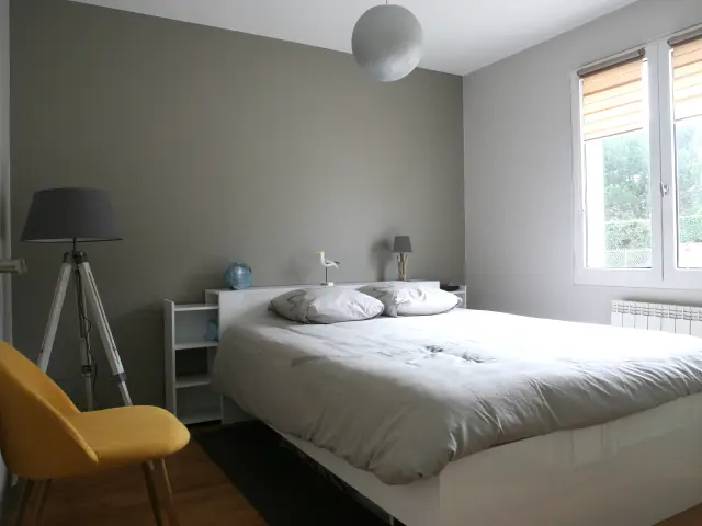 Chambre d'hôtel avec lit double, table de chevet, lampe, bureau et chaise