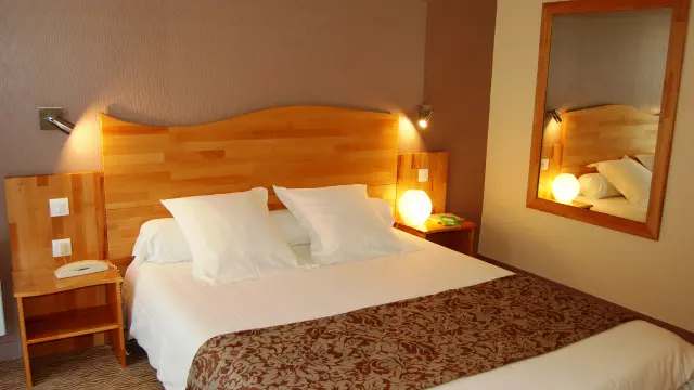 Chambre d'hôtel avec lit double, table de chevet, lampe et miroir mural