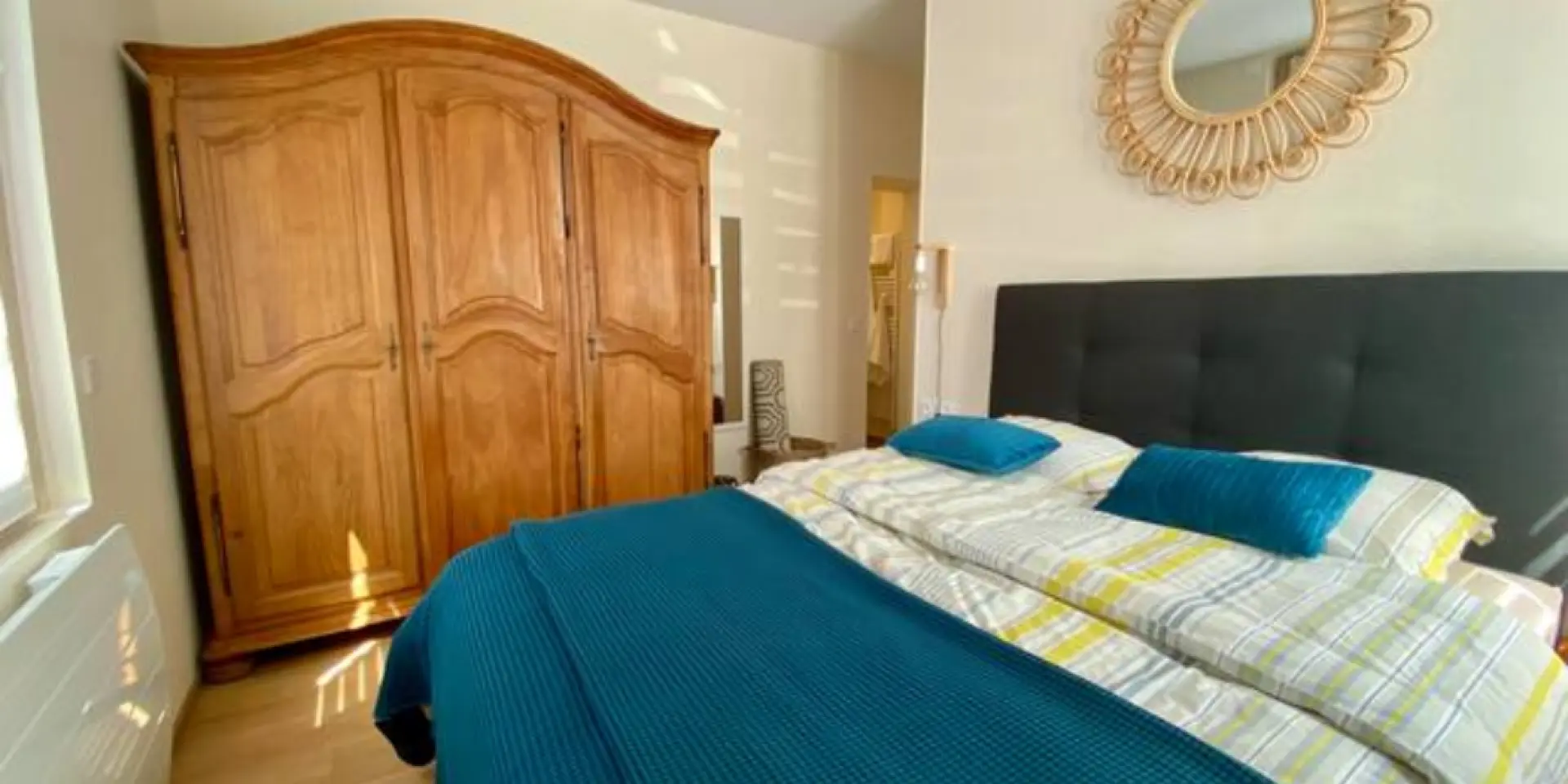 Bedroom with double bed, wooden wardrobe, and decorative mirror