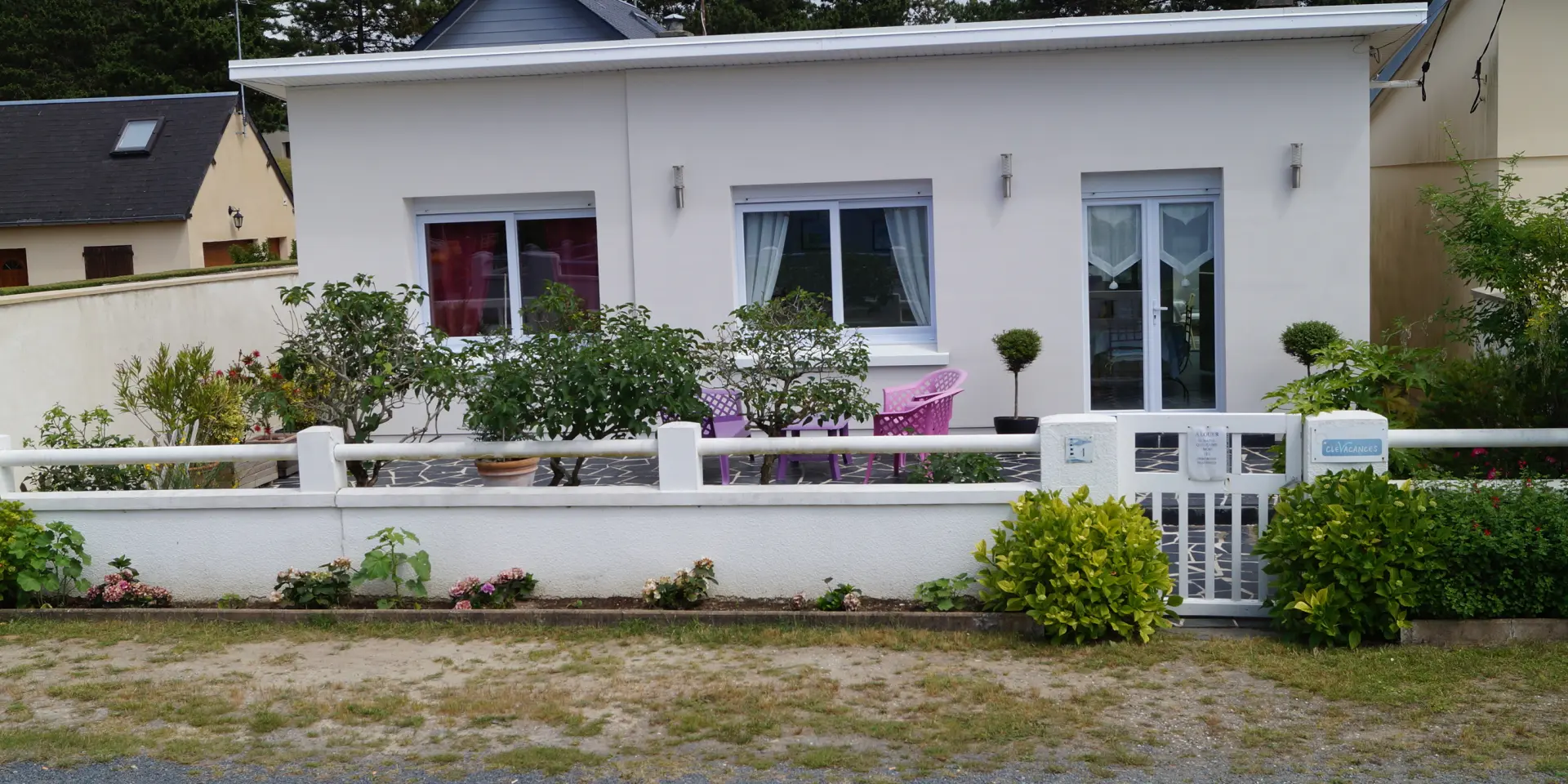 White house with flower garden and white fence