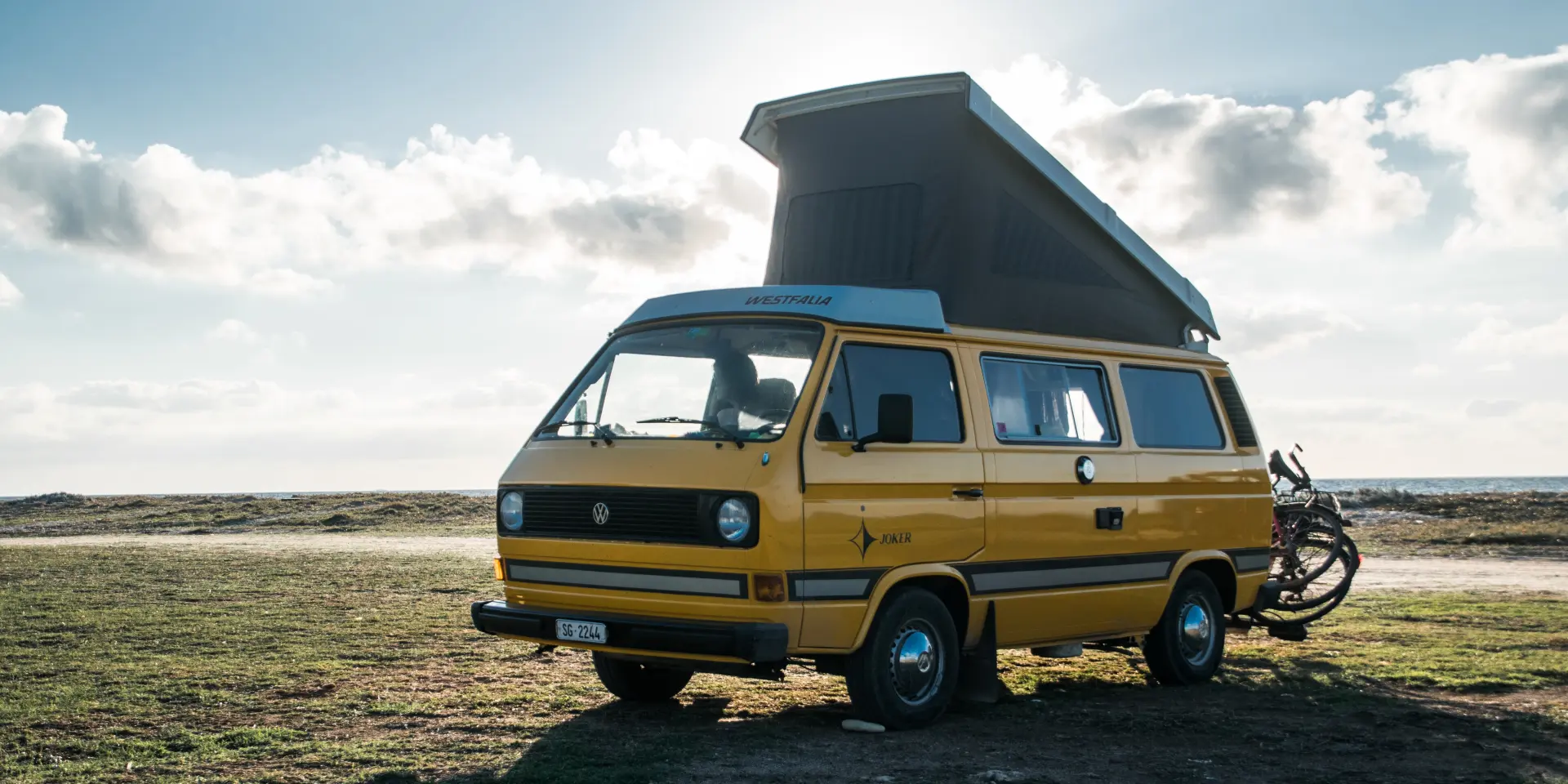 Camion jaune avec une caravane bleue sur une plage de sable