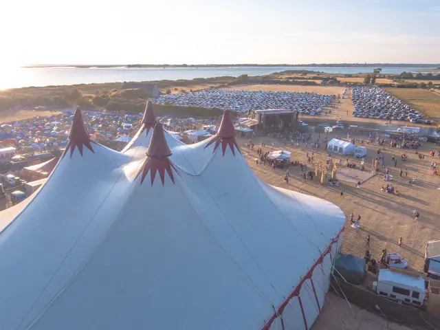 Vertäute Segelboote in einem Hafen bei Einbruch der Dunkelheit, mit beleuchteten Gebäuden im Hintergrund