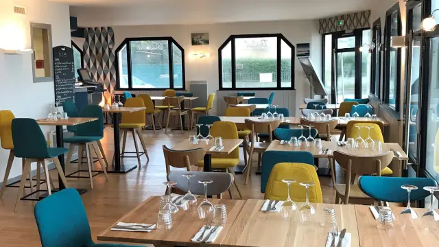 Salle de restaurant avec tables, chaises et comptoir de service éclairés par des lumières chaudes
