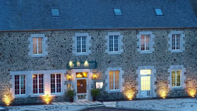 Maison en pierre avec fenêtres éclairées et jardin devant