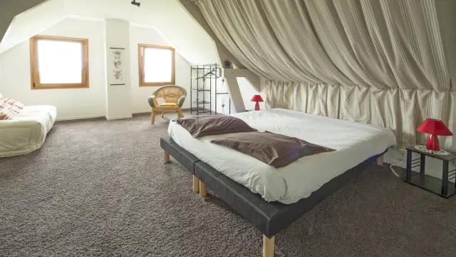 Chambre mansardée avec deux lits, des rideaux blancs et une décoration minimaliste