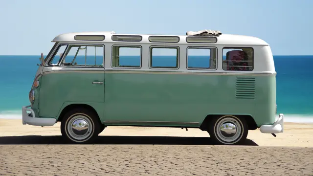 Un van vintage vert et blanc sur une plage de sable