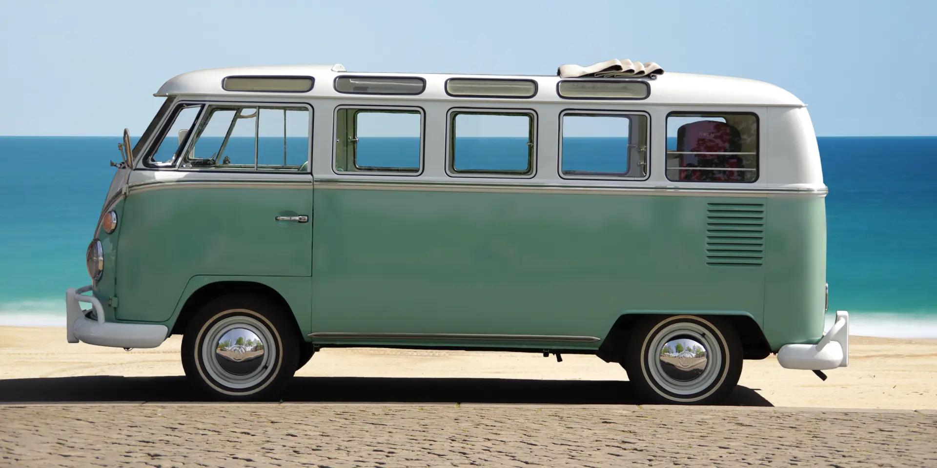 Un van vintage vert et blanc sur une plage de sable