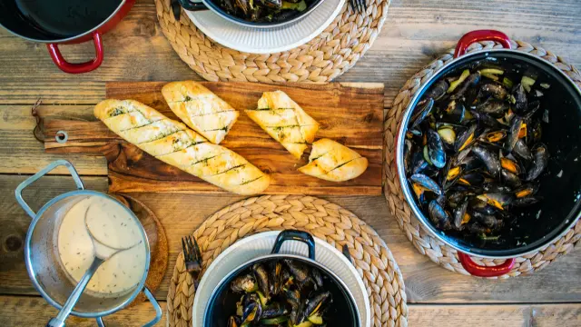 Assiettes de fruits de mer, salades et verres de vin sur une table en bois