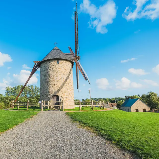 Stone windmill with wooden blades in a green field