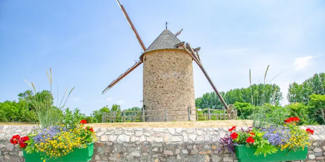 Stone tower with battlements, surrounded by flowers and rocks, by the seaside