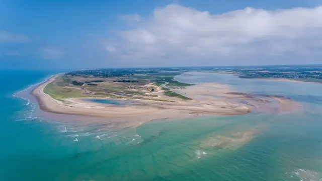 Île en forme de cœur entourée d’un lagon aux eaux turquoise, avec des bâtiments et des infrastructures visibles
