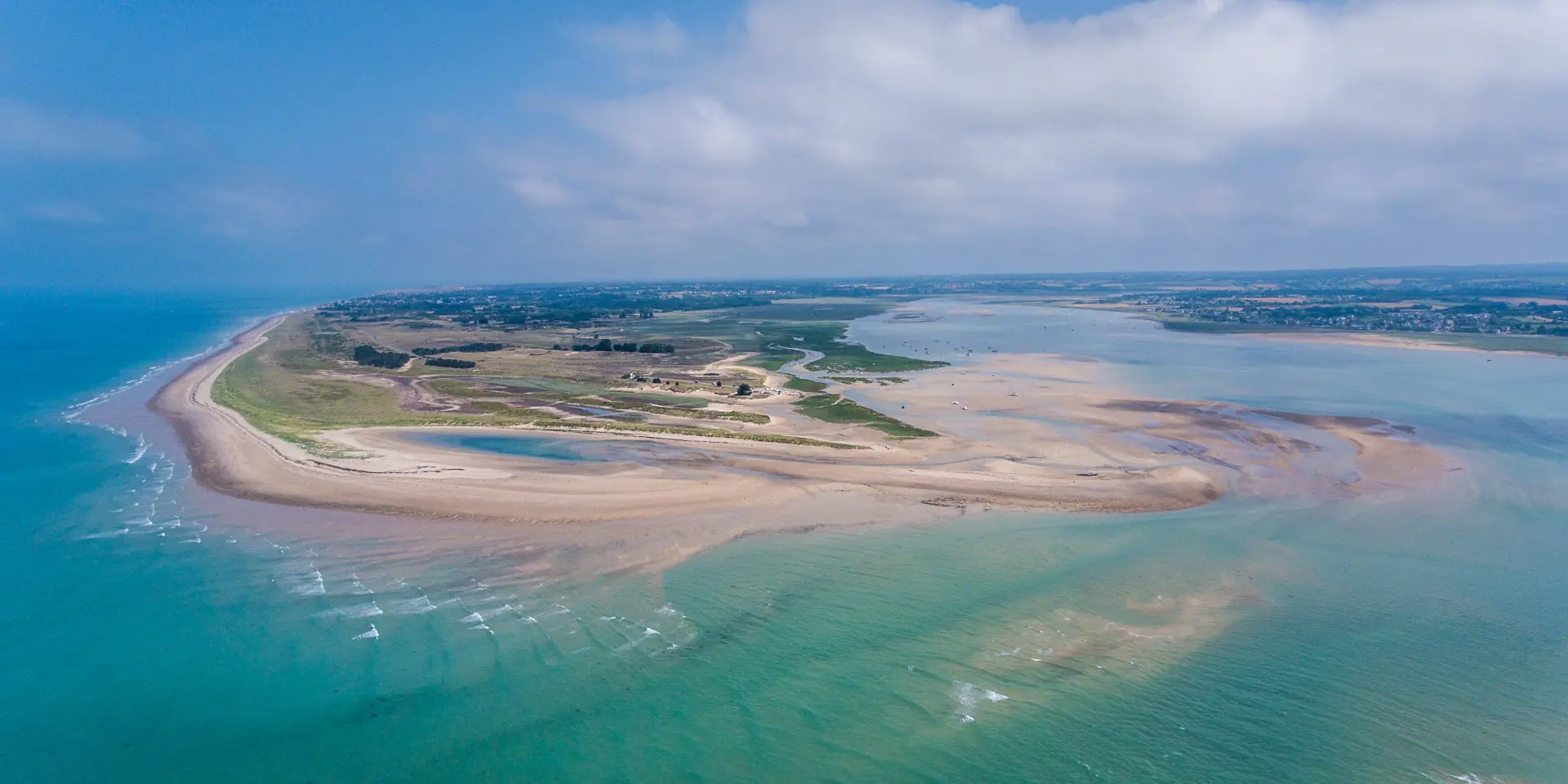 Île en forme de cœur entourée d’un lagon aux eaux turquoise, avec des bâtiments et des infrastructures visibles