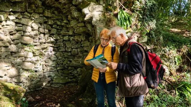 Zwei ältere Menschen konsultieren eine Karte in der Nähe einer Steinmauer im ländlichen Raum