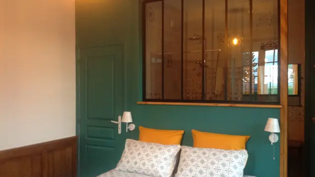 Schlafzimmer mit einem Doppelbett, grünen Wänden, Nachttischen und einem großen Fenster