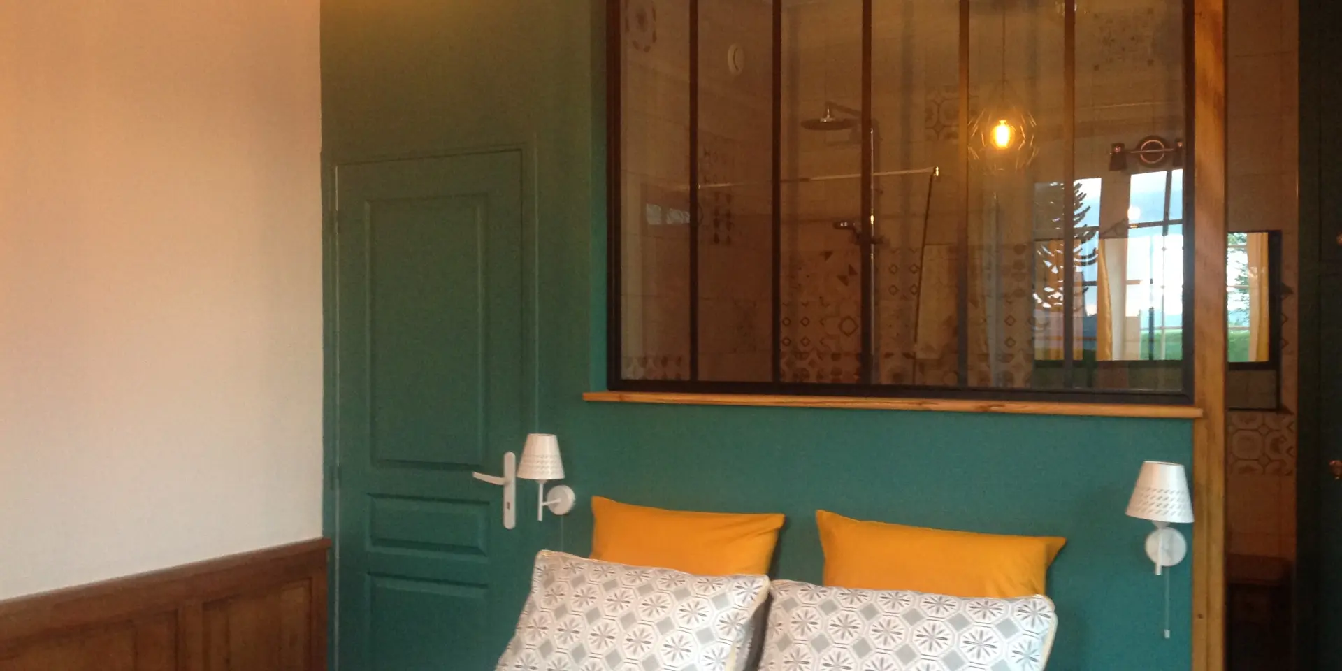 Schlafzimmer mit einem Doppelbett, grünen Wänden, Nachttischen und einem großen Fenster