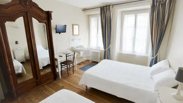 Zimmer mit zwei Betten, einem großen Spiegel, einem Fernseher und einem Fenster mit blauen Vorhängen