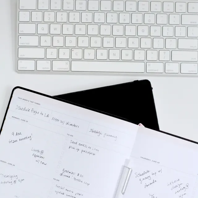 Un clavier blanc et un agenda ouvert avec des tâches écrites à la main