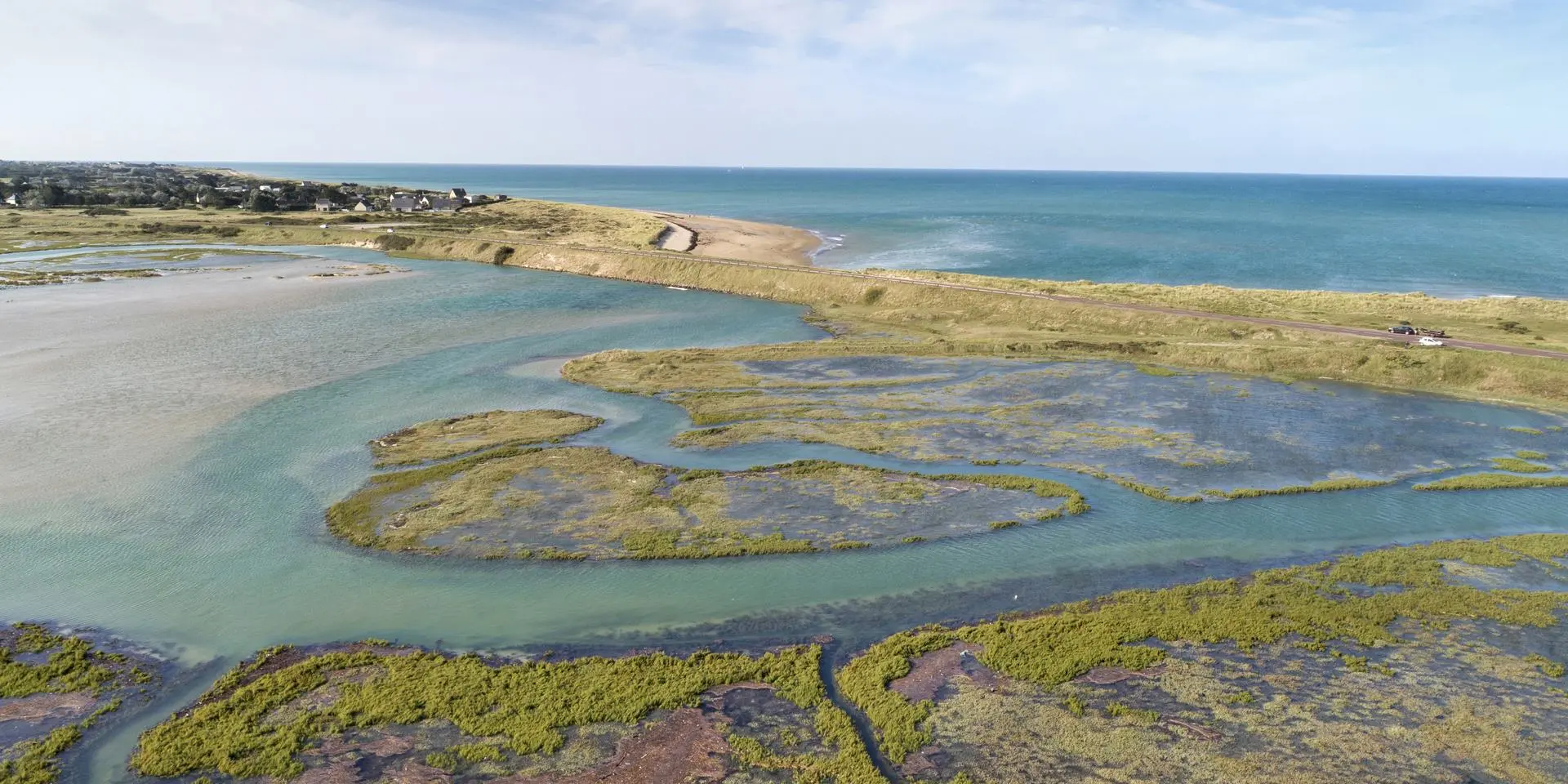 Luftaufnahme eines Küstenfeuchtgebiets mit Wasserkanälen und dem Ozean im Hintergrund