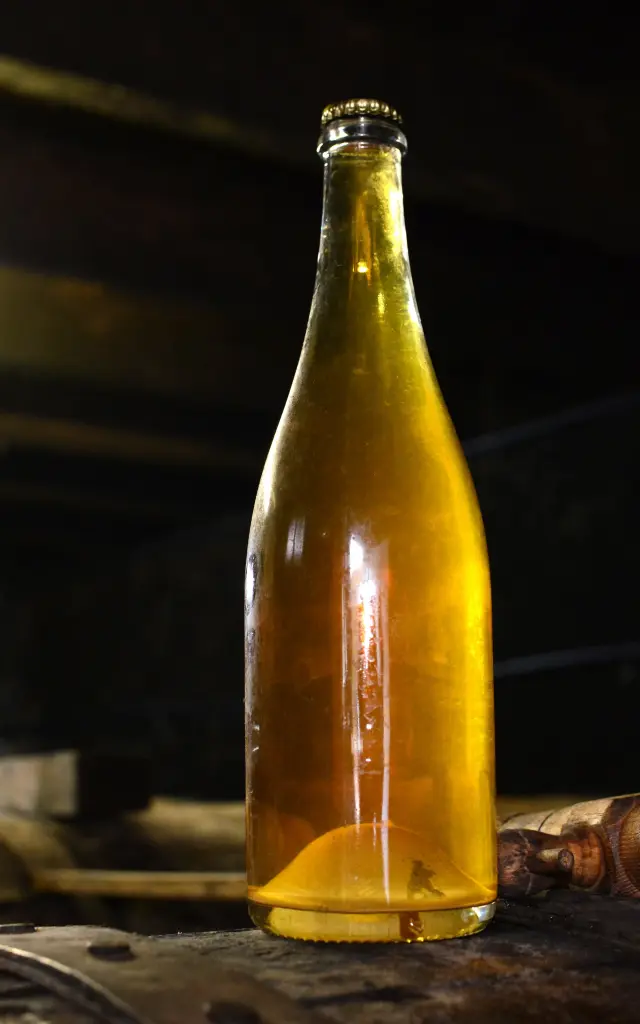 Bouteille de bière artisanale avec étiquette dorée posée sur une table en bois
