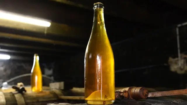 Bouteille de bière artisanale avec étiquette dorée posée sur une table en bois