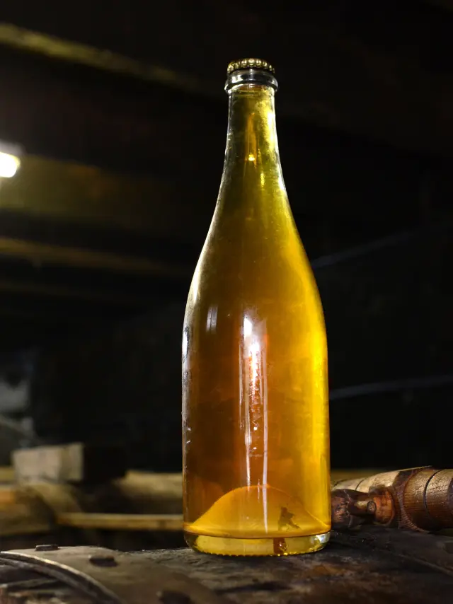 Deux bouteilles de cidre artisanal sur un tonneau en bois