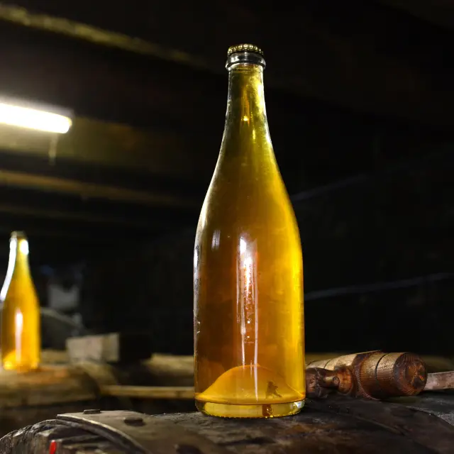 Bouteille de cidre artisanal posée sur un tonneau