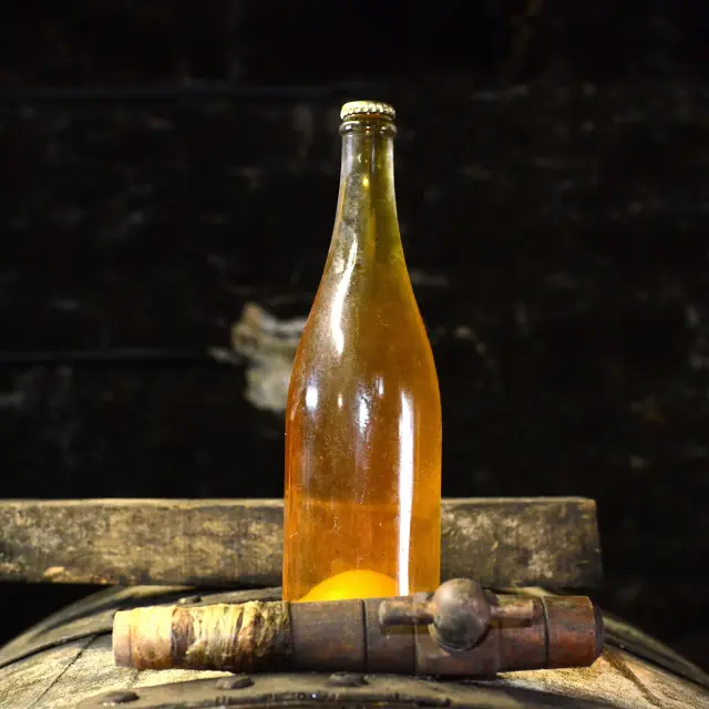 Beer bottle placed on a wooden barrel
