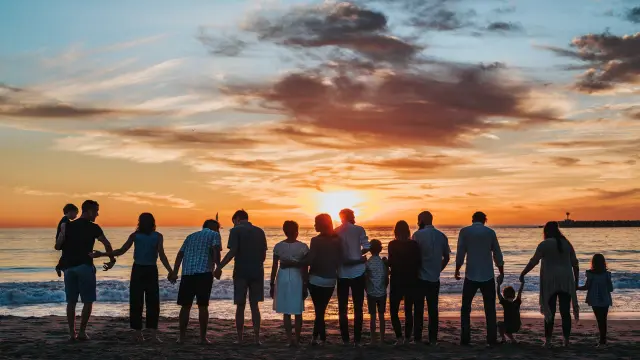 Groupe de personnes debout sur une plage au coucher du soleil