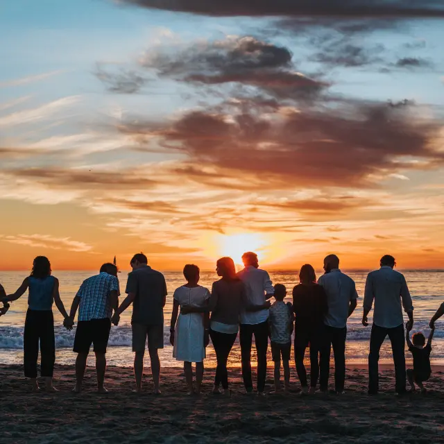 Groupe de personnes debout sur une plage au coucher du soleil