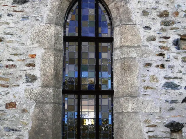Fenêtre gothique avec vitrail coloré dans un mur de pierre de l'Ermitage Saint Gerbold