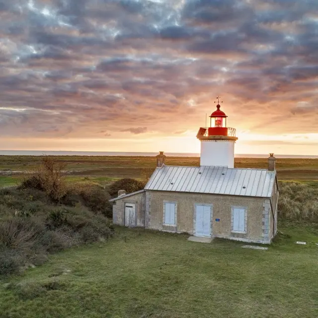 Einsamer Leuchtturm in einer grasbewachsenen Landschaft bei Sonnenuntergang