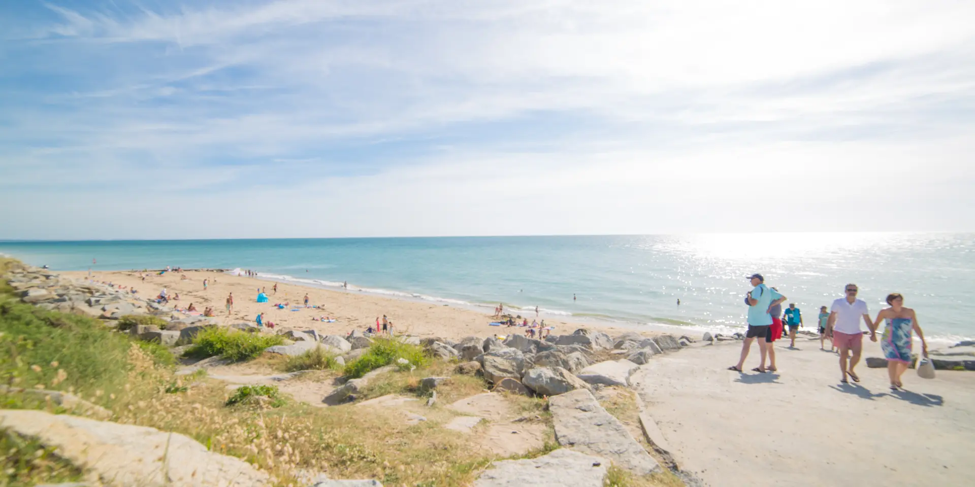 Gruppe von Menschen, die auf einem Küstenweg zu einem sonnigen Strand gehen