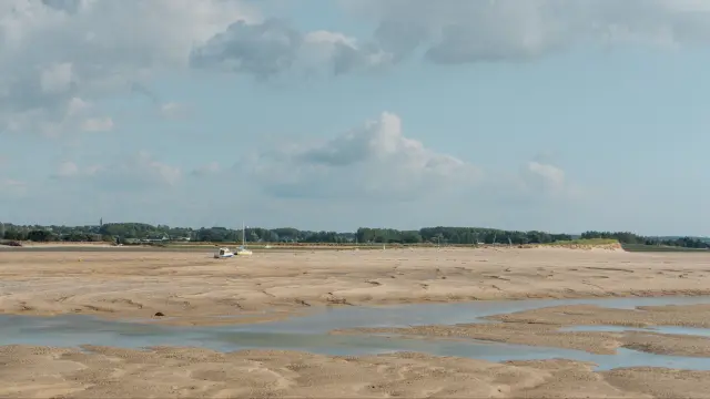 Sandy beach with water puddles and a cloudy sky